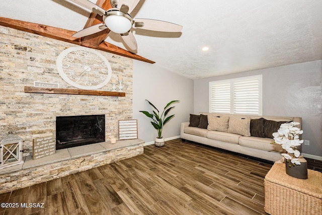 living room featuring vaulted ceiling, a stone fireplace, hardwood / wood-style flooring, ceiling fan, and a textured ceiling