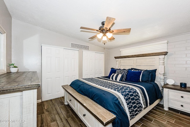 bedroom featuring multiple closets, lofted ceiling, dark wood-type flooring, and ceiling fan