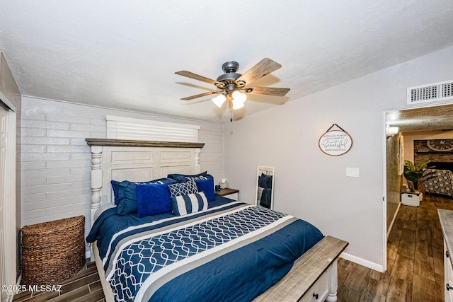 bedroom with ceiling fan, dark hardwood / wood-style floors, and a textured ceiling