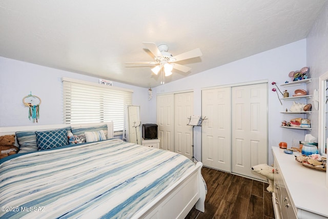 bedroom featuring ceiling fan, dark hardwood / wood-style flooring, vaulted ceiling, and two closets