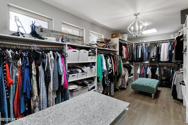 spacious closet with hardwood / wood-style flooring and a notable chandelier