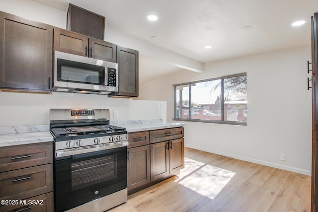 kitchen featuring dark brown cabinetry, stainless steel appliances, beam ceiling, and light hardwood / wood-style floors