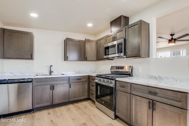 kitchen with sink, dark brown cabinetry, ceiling fan, stainless steel appliances, and light hardwood / wood-style flooring