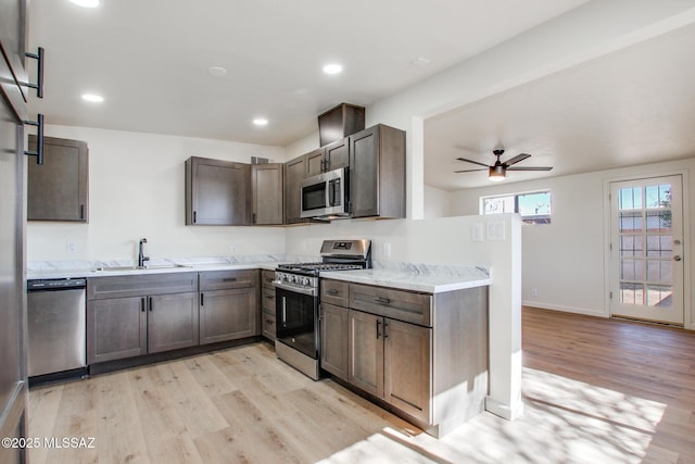 kitchen with ceiling fan, appliances with stainless steel finishes, sink, and light hardwood / wood-style floors