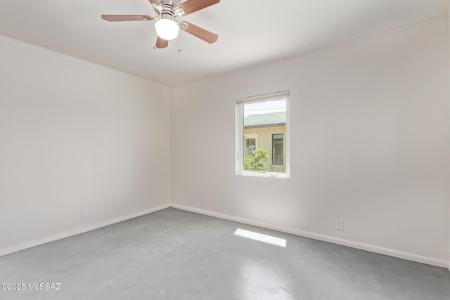 spare room featuring baseboards, concrete flooring, and a ceiling fan