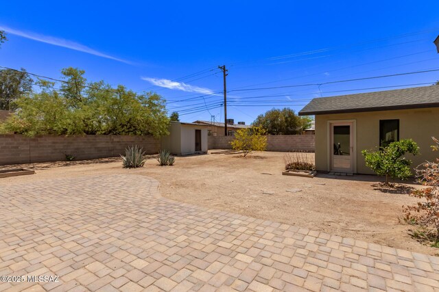 fenced backyard with an outbuilding and a patio