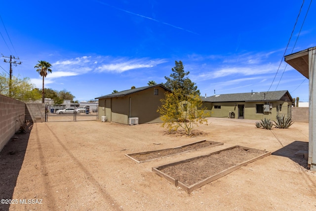rear view of property featuring a gate, fence, and a vegetable garden