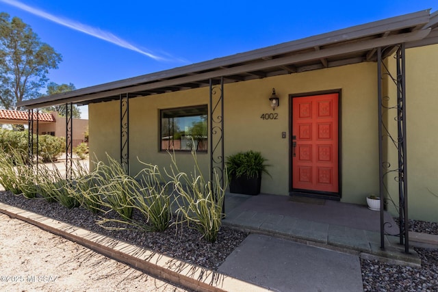 property entrance featuring stucco siding and covered porch