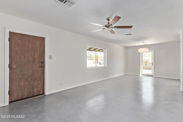 spare room featuring healthy amount of natural light, concrete floors, and a ceiling fan