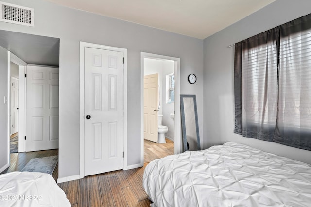 bedroom featuring hardwood / wood-style flooring, connected bathroom, and multiple windows