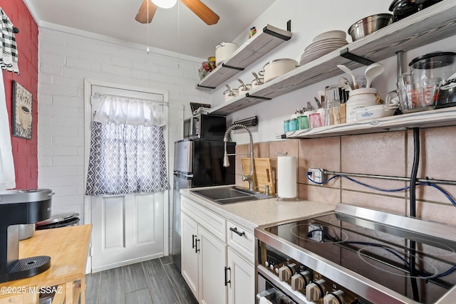 kitchen featuring white cabinetry, electric stove, ceiling fan, brick wall, and decorative backsplash