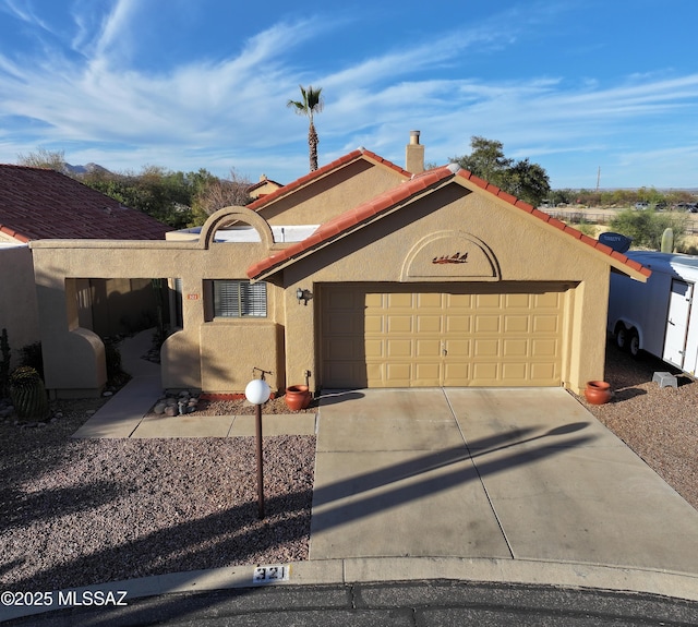 view of front of property featuring a garage, driveway, a tiled roof, and stucco siding