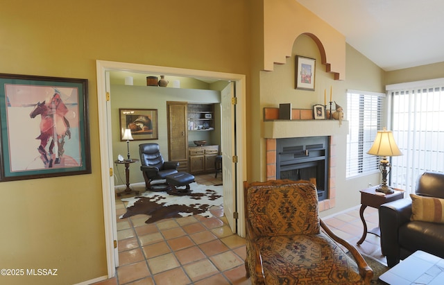 sitting room featuring vaulted ceiling, a fireplace, tile patterned flooring, and baseboards