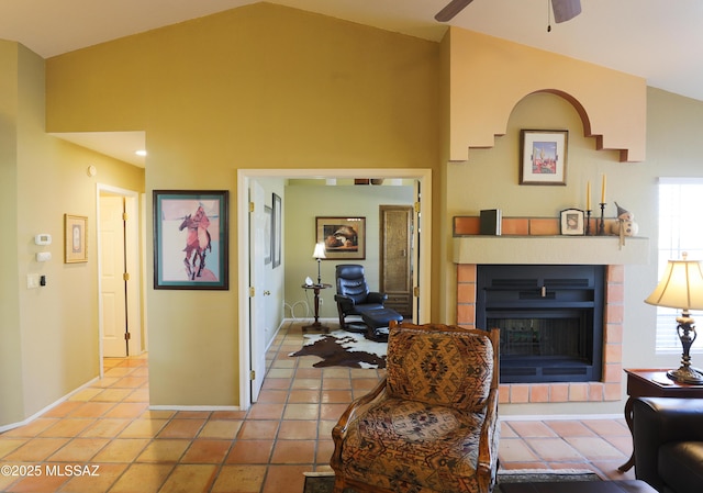 living area with light tile patterned floors, baseboards, ceiling fan, a fireplace, and high vaulted ceiling