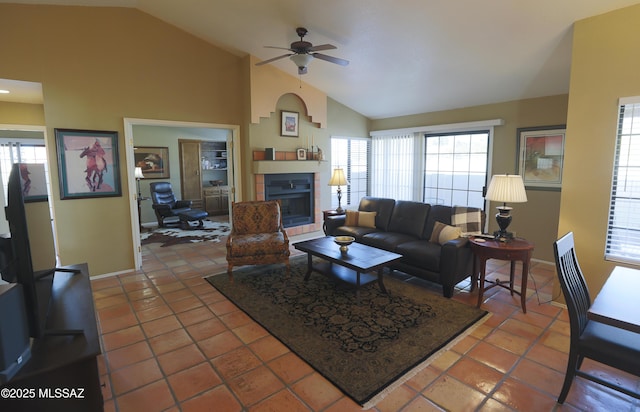 tiled living room with ceiling fan, high vaulted ceiling, a fireplace, and baseboards