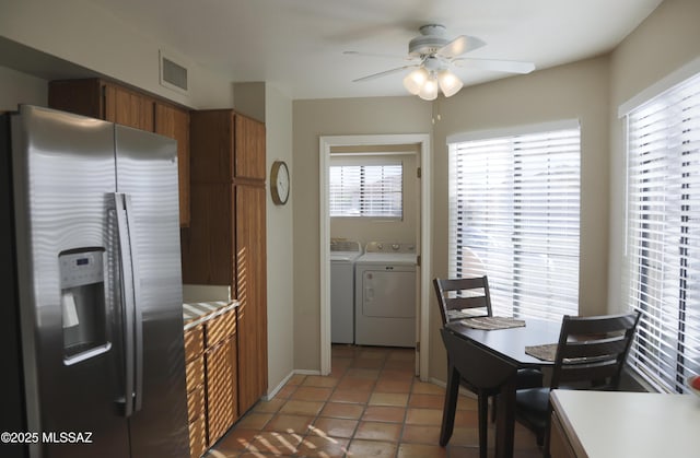 kitchen featuring light countertops, brown cabinetry, stainless steel refrigerator with ice dispenser, and washing machine and clothes dryer