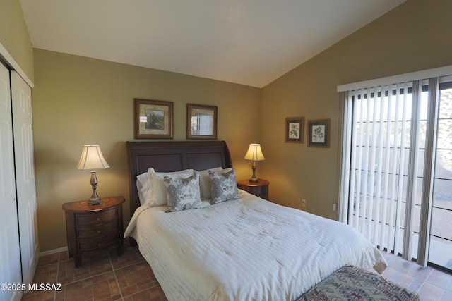 bedroom featuring access to outside, baseboards, vaulted ceiling, and a closet