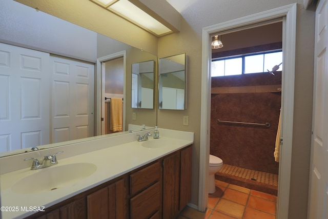 bathroom with double vanity, tile patterned flooring, a sink, and toilet