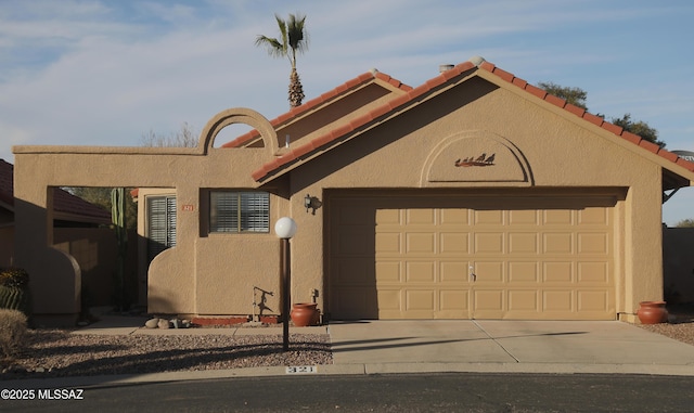 view of front of property with driveway, an attached garage, a tiled roof, and stucco siding