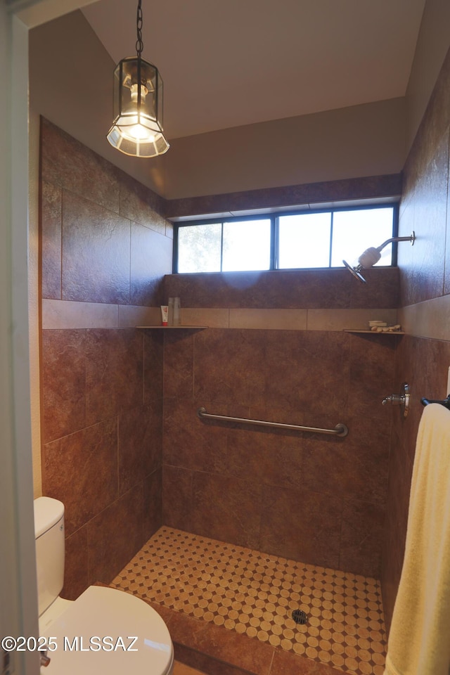 bathroom with a tile shower and toilet