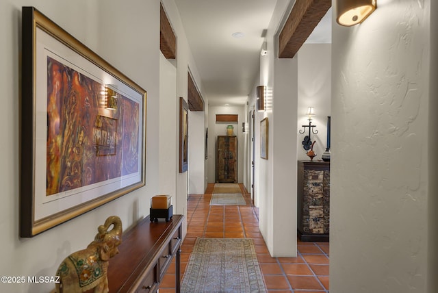 hall featuring tile patterned flooring and beam ceiling