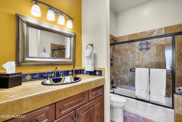 full bathroom with vanity, bath / shower combo with glass door, tile patterned floors, and toilet