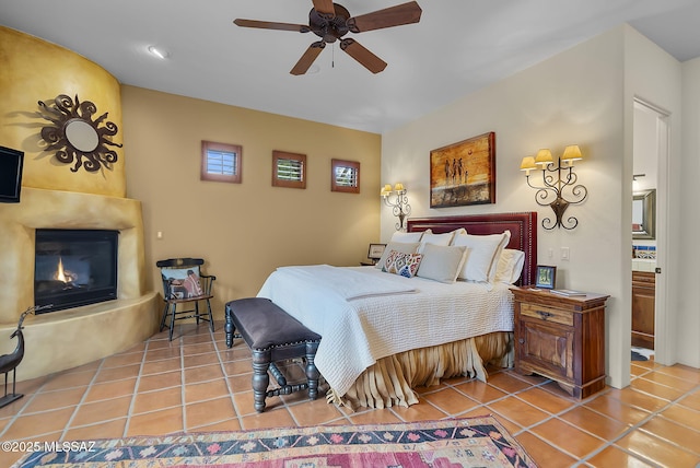 tiled bedroom featuring a fireplace and ceiling fan