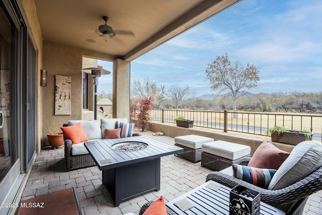 view of patio / terrace with ceiling fan and an outdoor living space with a fire pit