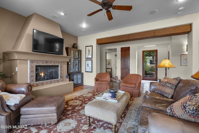 living room with a tiled fireplace, wood-type flooring, lofted ceiling, and ceiling fan