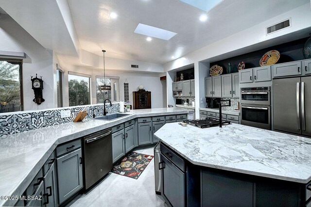 12342 E Barry Baker Pl, Tucson, AZ 85749 - kitchen with a spacious island, gray cabinets, a sink, appliances with stainless steel finishes, and a skylight