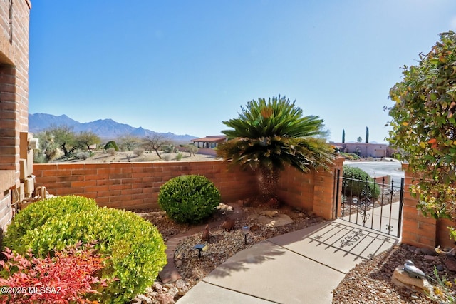 view of yard featuring a gate, fence, and a mountain view