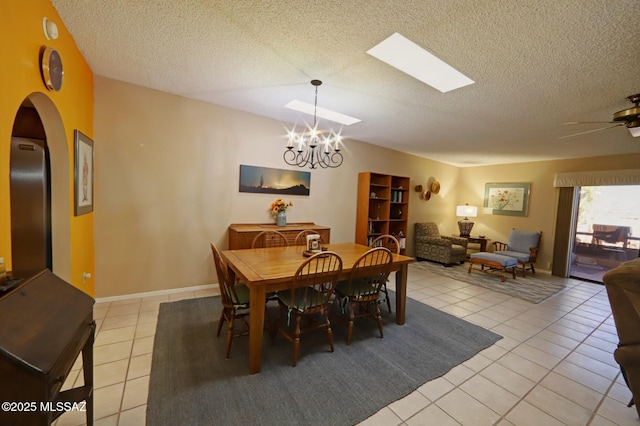 tiled dining area featuring ceiling fan with notable chandelier and a textured ceiling