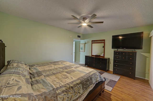 bedroom with ceiling fan, a textured ceiling, and light hardwood / wood-style flooring