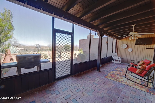 sunroom featuring ceiling fan and beamed ceiling