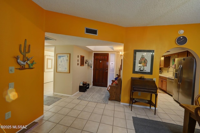 foyer entrance with sink, a textured ceiling, and light tile patterned floors