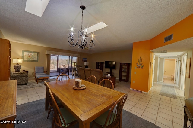 tiled dining area with lofted ceiling with skylight, a chandelier, and a textured ceiling