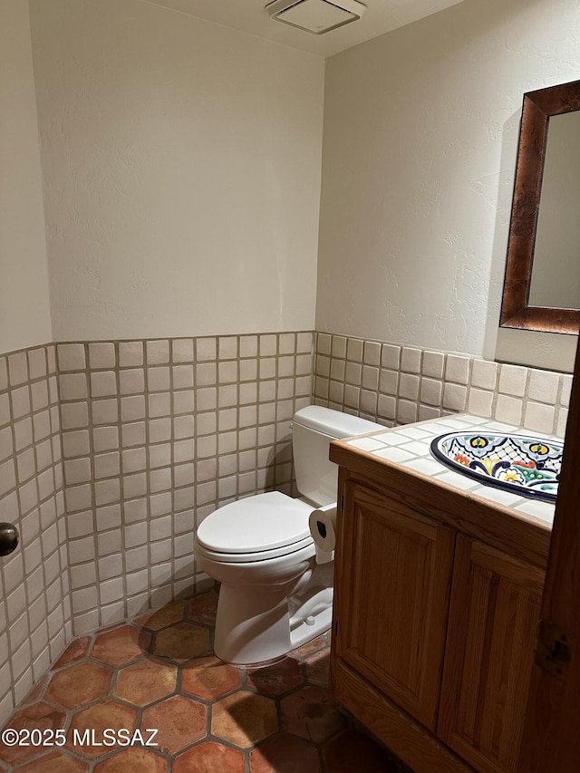 bathroom with tile walls, vanity, tile patterned flooring, and toilet