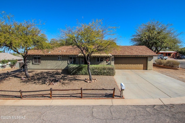 ranch-style home featuring a fenced front yard, driveway, a garage, and stucco siding