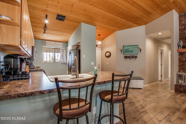 kitchen featuring visible vents, wood ceiling, a peninsula, stainless steel appliances, and a stone fireplace