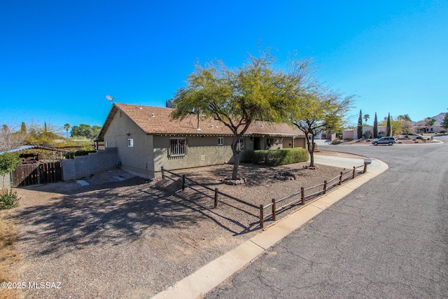 ranch-style house featuring fence and stucco siding