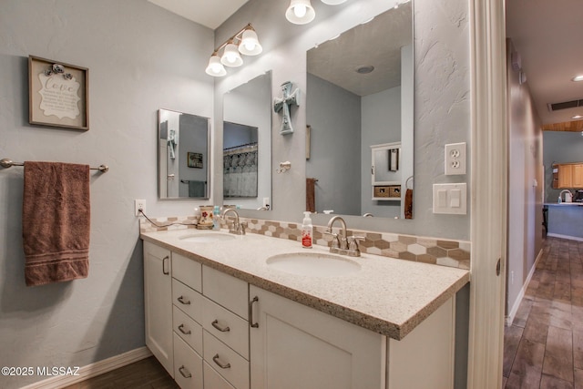 full bath with visible vents, backsplash, a sink, and wood finished floors