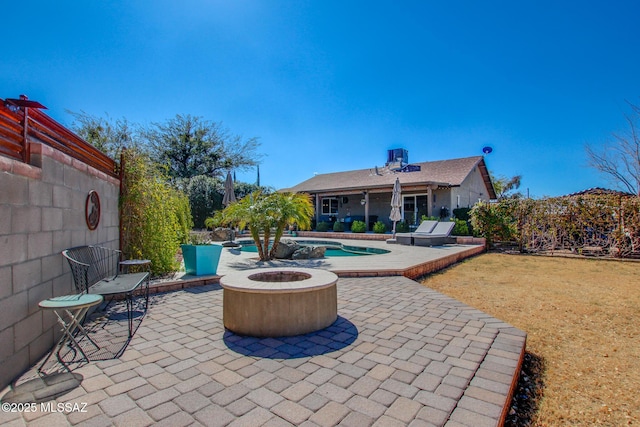 view of patio with a fenced backyard, an outdoor pool, and a fire pit