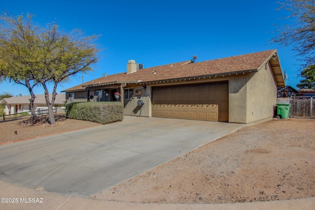 single story home featuring an attached garage, fence, concrete driveway, roof with shingles, and stucco siding