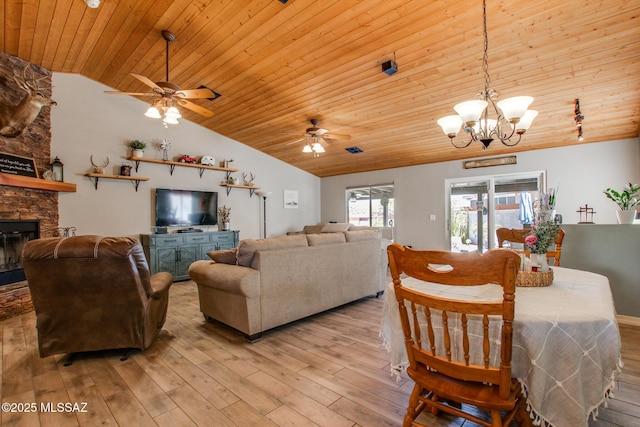 living area featuring light wood-style floors, vaulted ceiling, a stone fireplace, wooden ceiling, and ceiling fan with notable chandelier