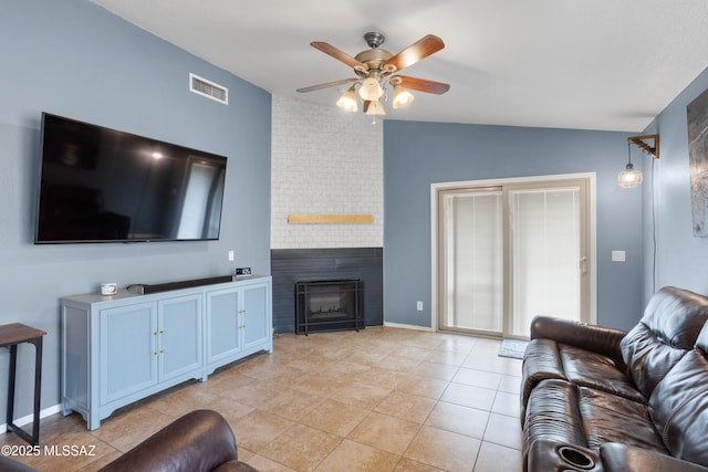 tiled living room featuring a brick fireplace, vaulted ceiling, and ceiling fan