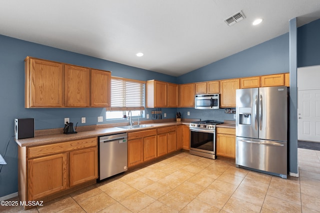 kitchen with light tile patterned flooring, lofted ceiling, appliances with stainless steel finishes, and sink