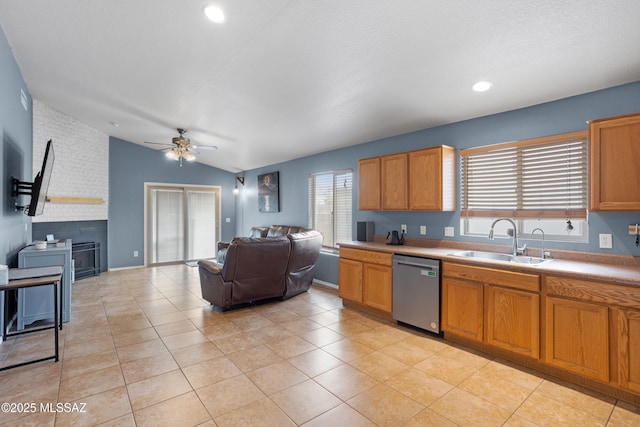 kitchen featuring lofted ceiling, sink, dishwasher, light tile patterned flooring, and a brick fireplace