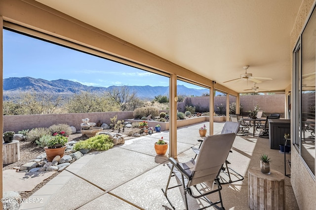 view of patio with a fenced backyard, outdoor dining space, a mountain view, and ceiling fan