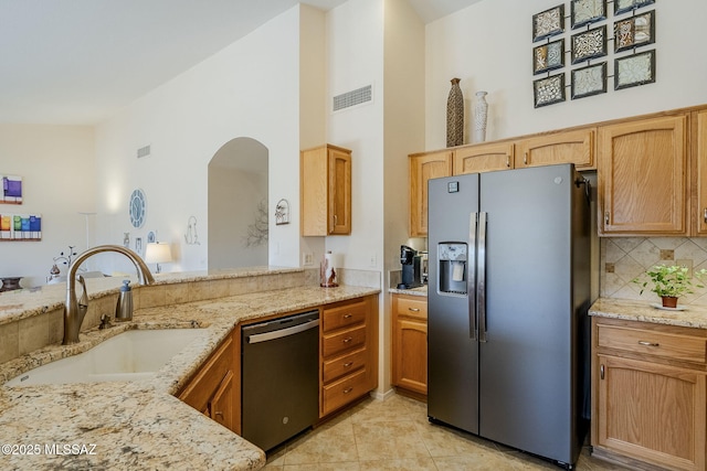 kitchen with tasteful backsplash, light stone countertops, light tile patterned floors, stainless steel appliances, and a sink