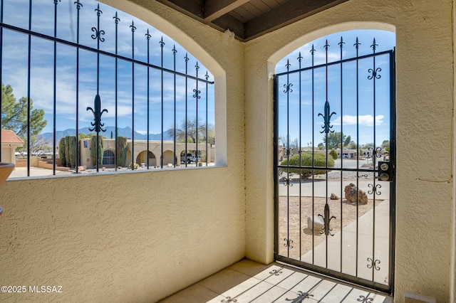 doorway to outside with tile patterned flooring, a mountain view, a wealth of natural light, and a textured wall